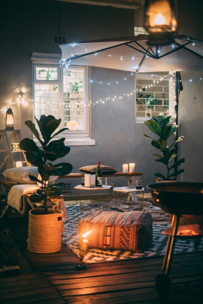 Intimate outdoor setup with string lights, cozy seating, and candles for a relaxing evening.